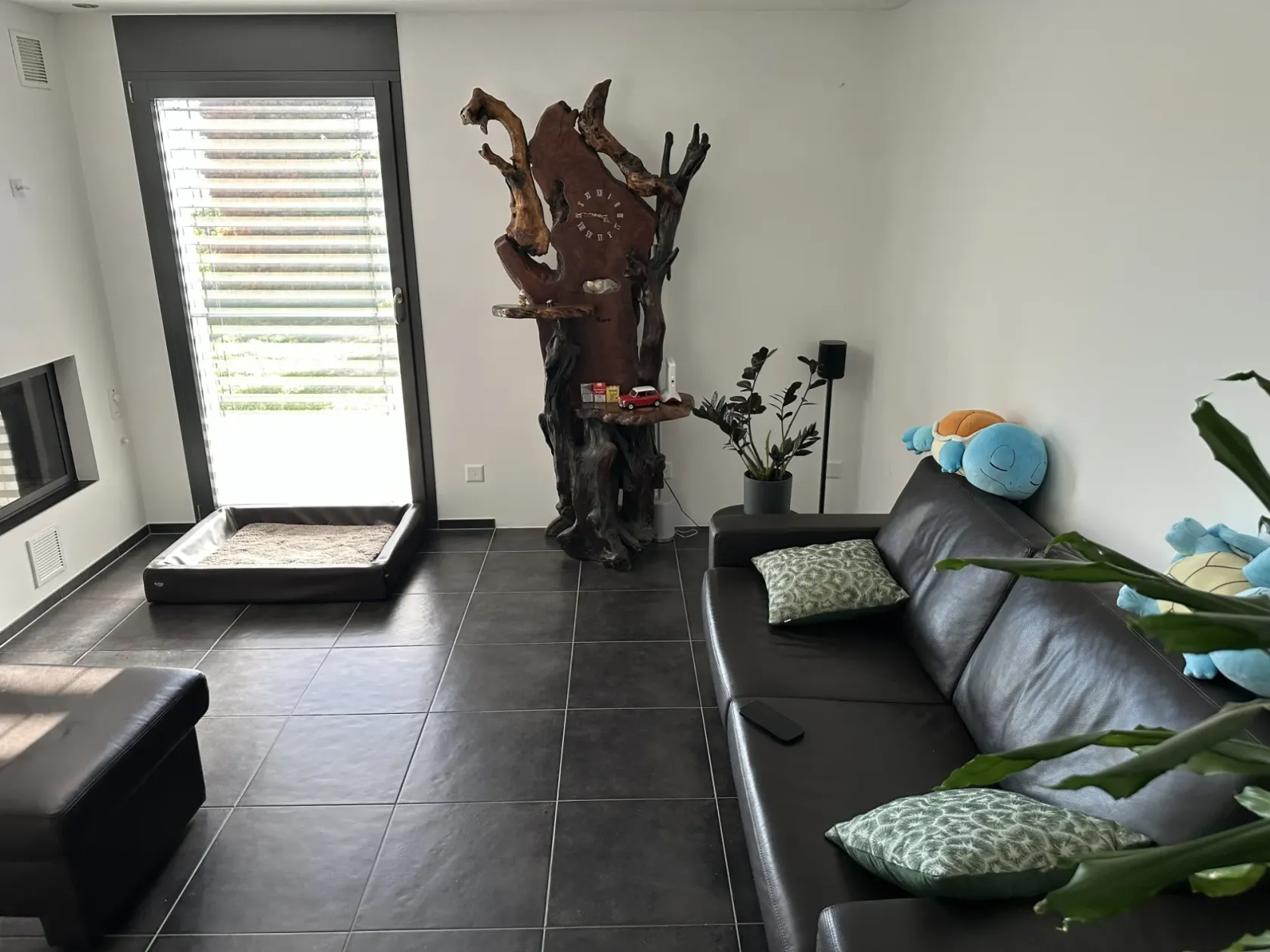 Der Ausgangszustand. An der Wand rechts der Terrassentür, wo das Becken hinkommt, stehen noch die Holzskulptur mit der Uhr, eine Pflanze und ein Lautsprecher, rechts daneben das Ledersofa. Vor der Tür liegt das Hundebett.